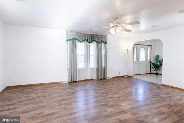 an empty room with wooden floor fan and windows