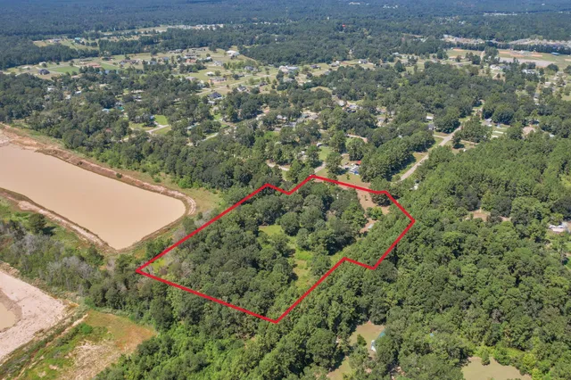 an aerial view of a houses with a yard and lake
