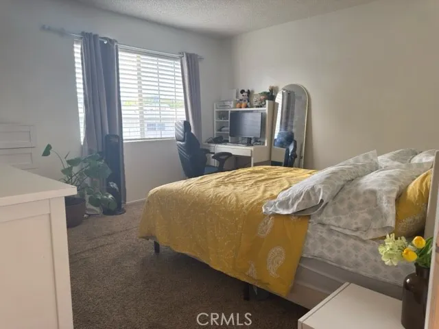 a bedroom with a bed and a potted plant on the dresser