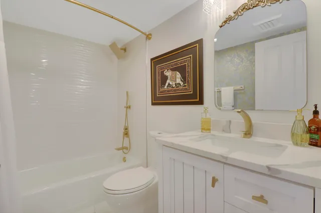 a spacious bedroom with a bed and a flat tv screen on dresser