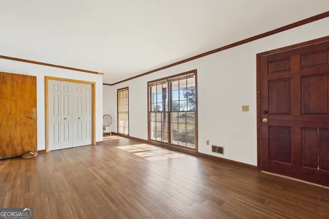 a view of an empty room with wooden floor and a window