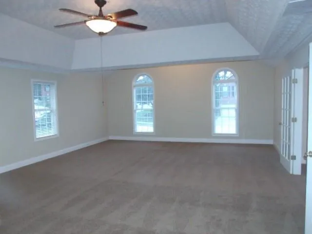 en empty room with windows and chandelier fan