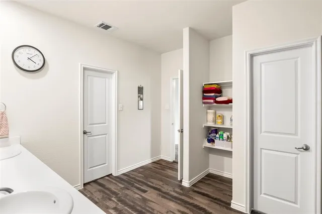 a bedroom with a bed and dresser with wooden floor