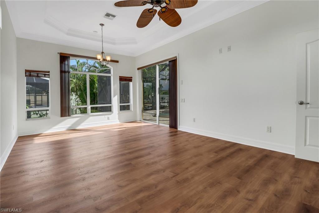 15480 River By Road Fort Myers, FL 33908 - Photo 22 of 48 Spare room with a raised ceiling, ceiling fan with notable chandelier, dark wood-type flooring, and crown molding