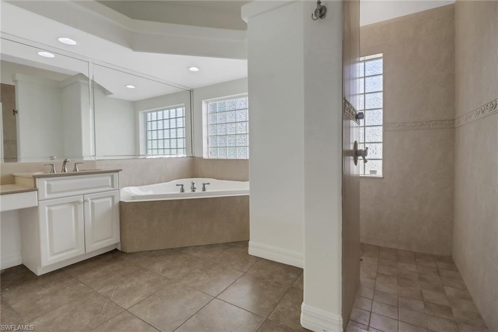 15480 River By Road Fort Myers, FL 33908 - Photo 25 of 48 Bathroom featuring tiled tub, a healthy amount of sunlight, vanity, and tile patterned floors