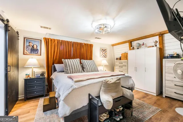 a bedroom with a bed a television and a large mirror on the dresser