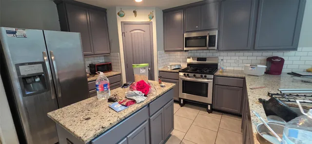 a kitchen with stainless steel appliances kitchen island granite countertop a refrigerator stove and sink