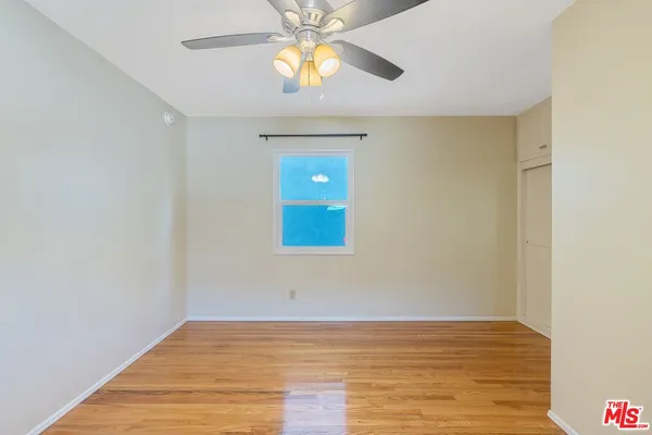 a view of an empty room with window and wooden floor
