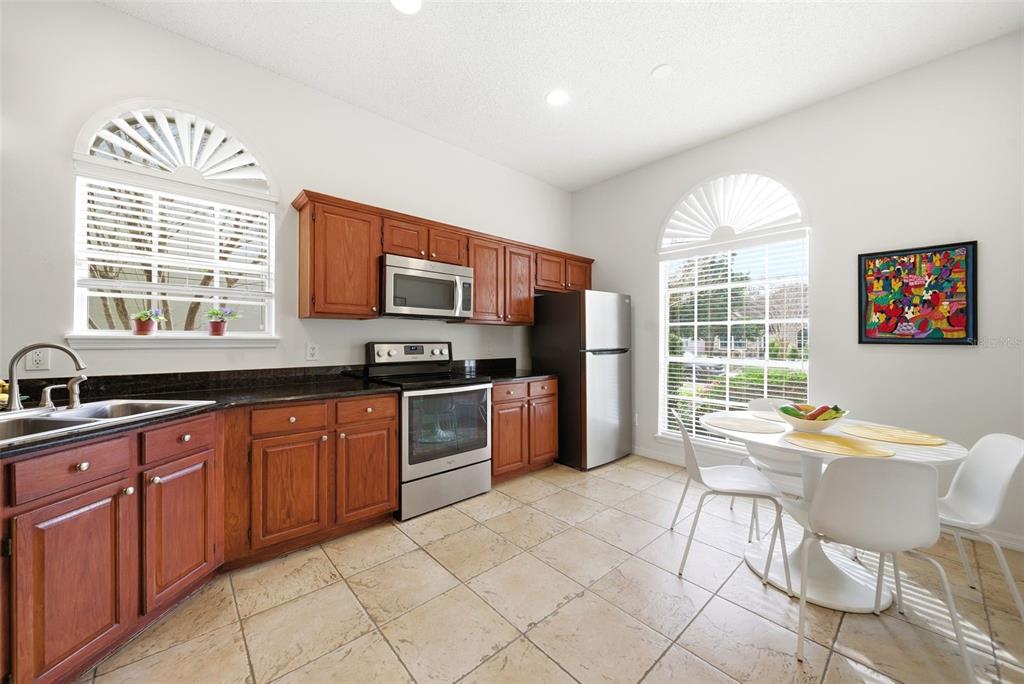 5452 Endicott Place Oviedo, FL 32765 - Photo 6 of 38 a kitchen with stainless steel appliances granite countertop a stove a sink dishwasher a dining table and chairs with wooden floor