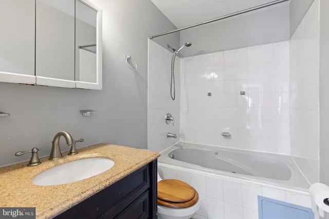 a bathroom with a granite countertop sink a toilet and bathtub