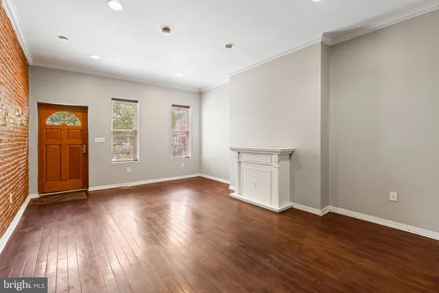 a view of an empty room with wooden floor and windows
