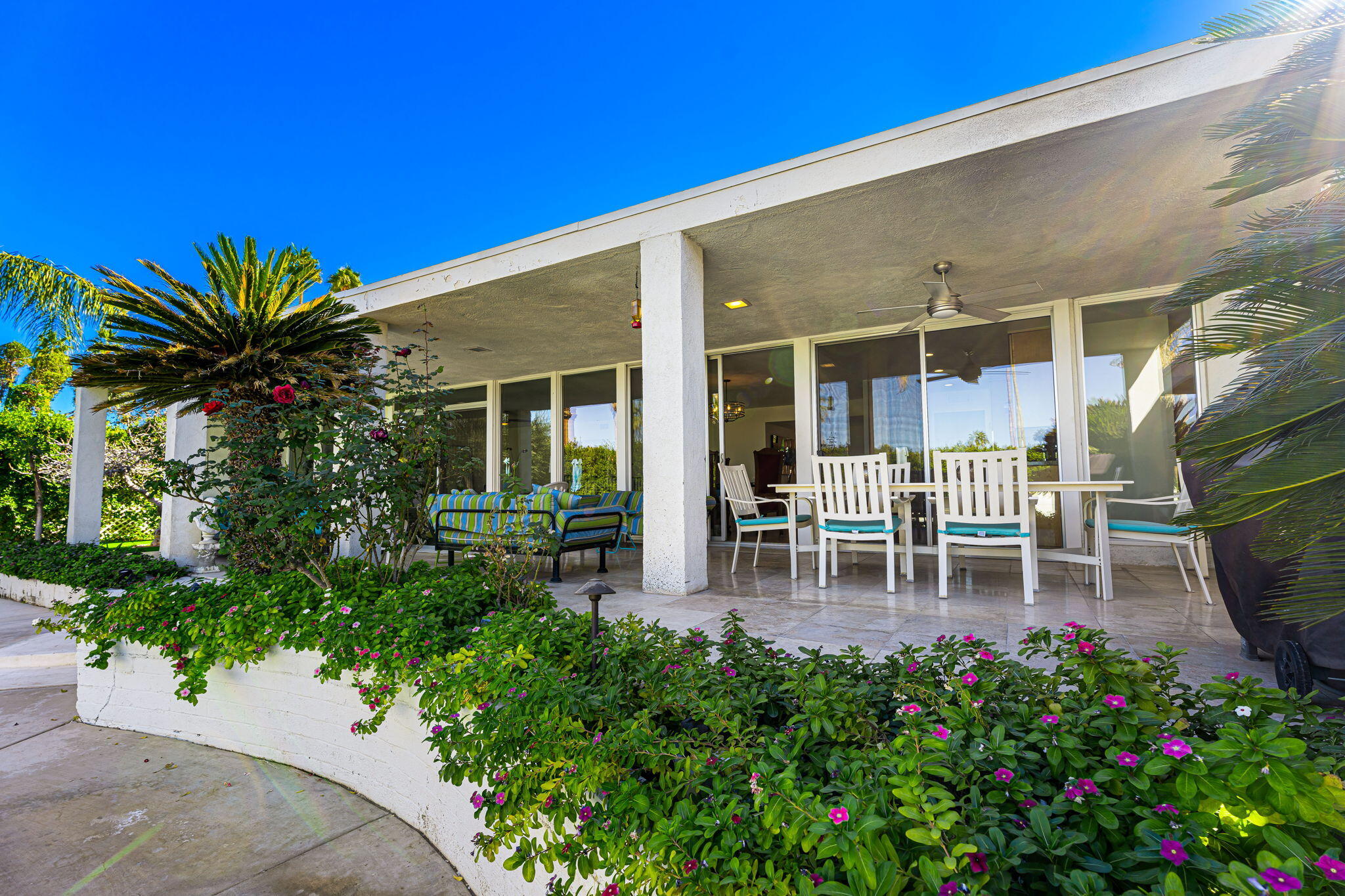 72890 Homestead Road Palm Desert, CA 92260 - Photo 28 of 45 a view of a patio with table and chairs potted plants and floor to ceiling window