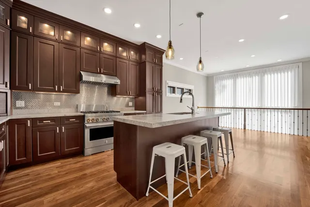 a kitchen with stainless steel appliances granite countertop wooden floors stove and cabinets