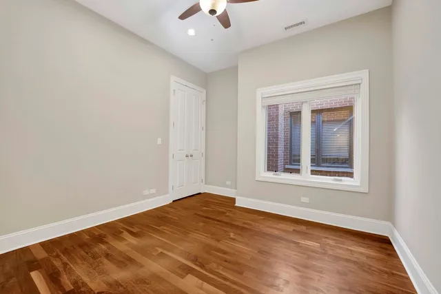 an empty room with wooden floor cabinet and chandelier fan