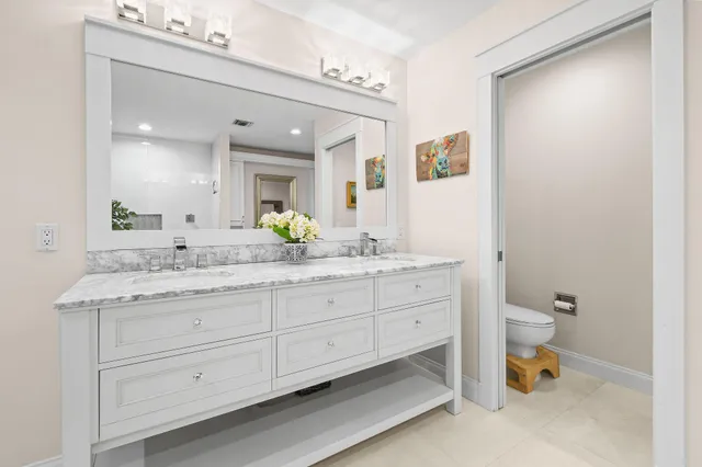a bathroom with a granite countertop sink mirror and toilet