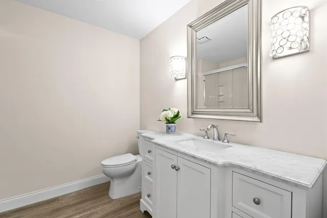 a bathroom with a granite countertop sink a toilet and a mirror