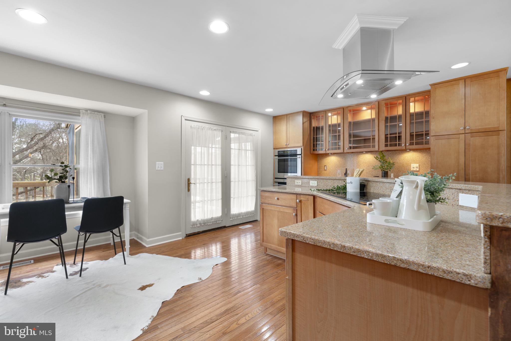 6968 Sunfleck Row Columbia, MD 21045 - Photo 7 of 45 a kitchen with stainless steel appliances granite countertop sink microwave and wooden floor