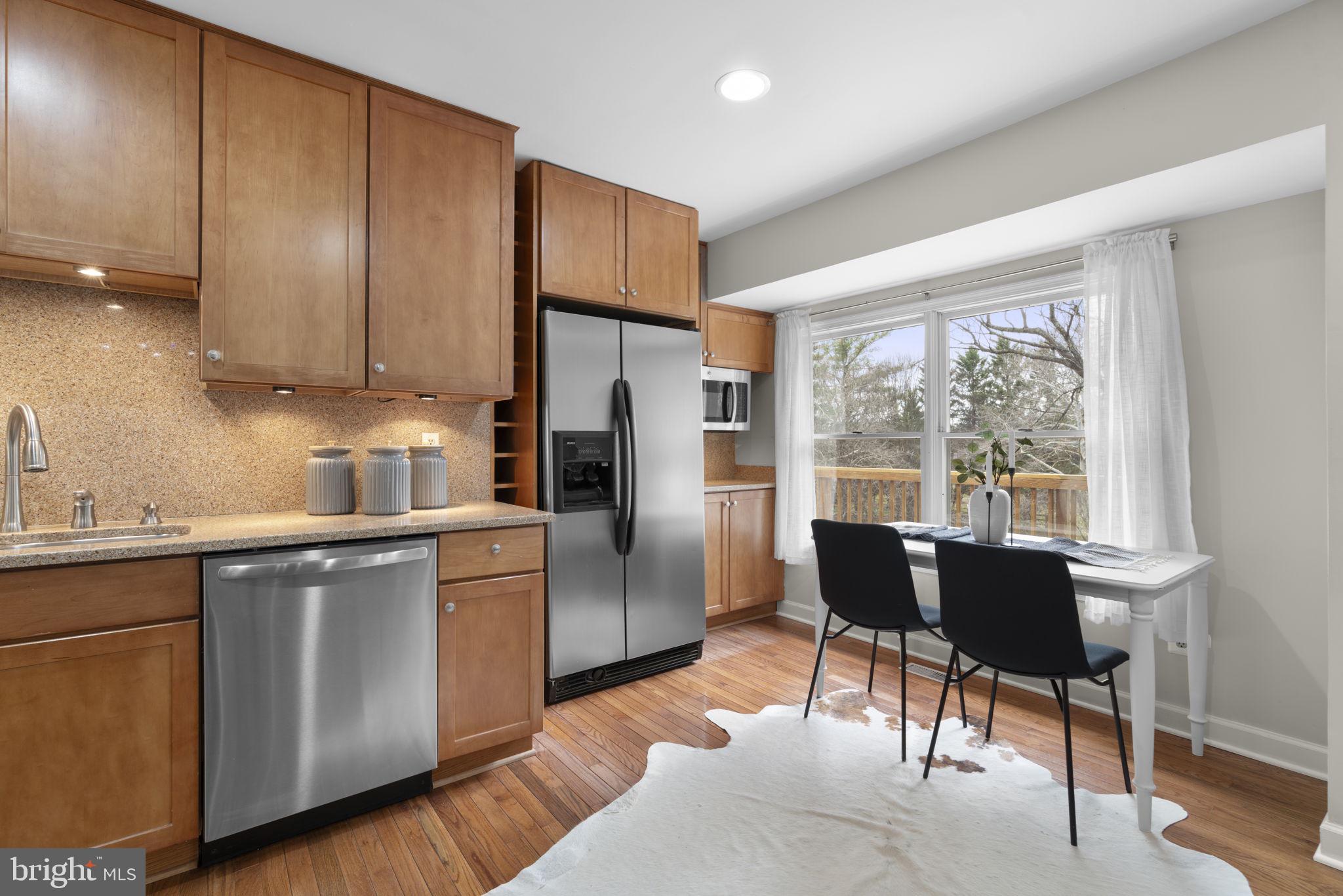 6968 Sunfleck Row Columbia, MD 21045 - Photo 9 of 45 a kitchen with stainless steel appliances granite countertop a refrigerator a sink a stove a dining table and chairs