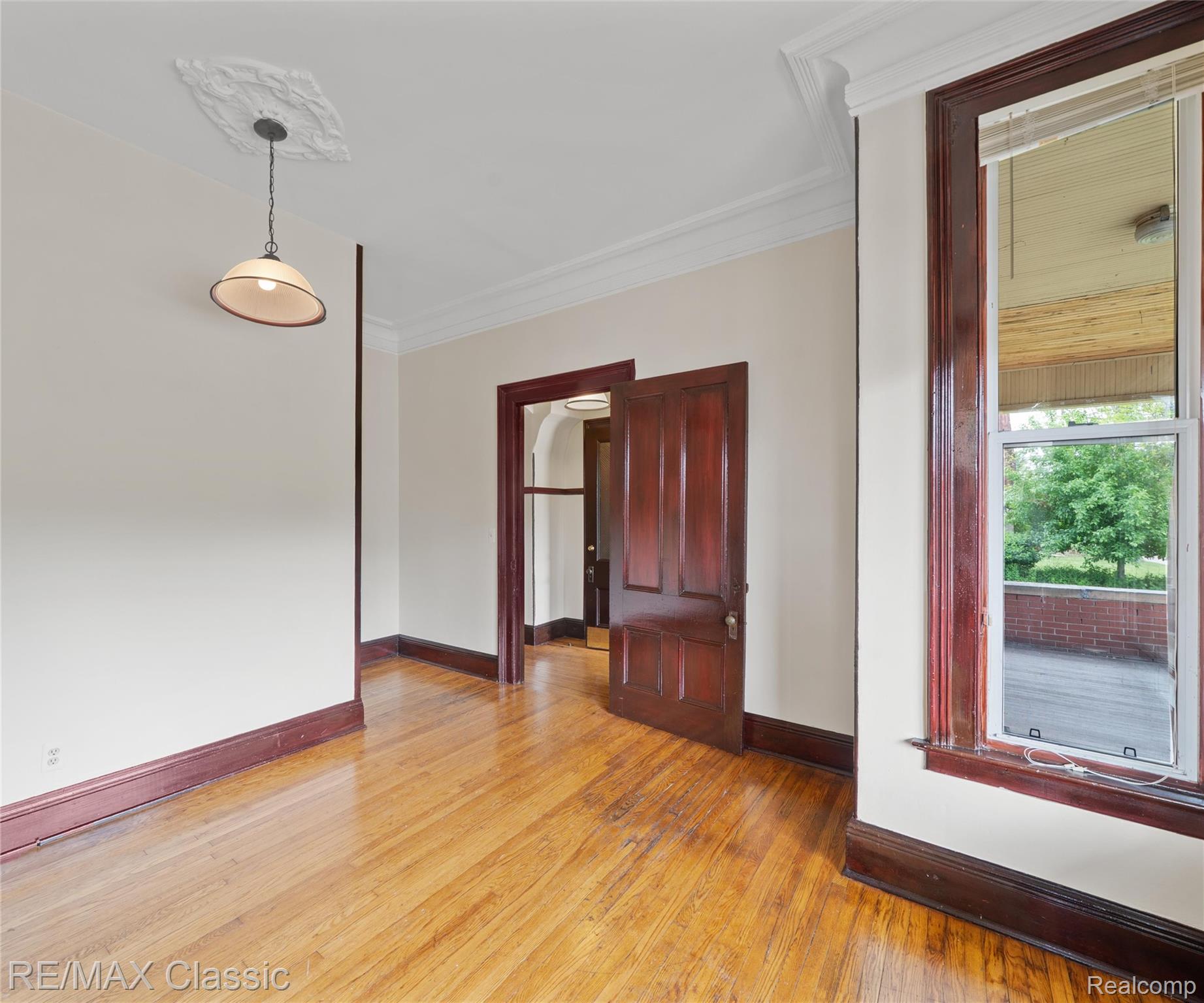 3941 Trumbull Detroit, MI 48208 - Photo 17 of 46 Hardwood flooring throughout featuring dark wood trim, crown molding, and a decorative ceiling medallion