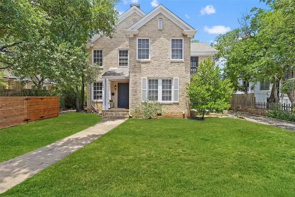 a front view of a house with a yard and trees