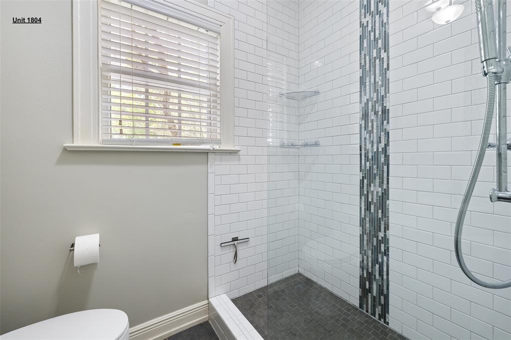 1806 Pearl Street Austin, TX 78701 - Photo 15 of 19 Shower enclosure featuring subway tile walls, a mosaic tile accent strip, and a dark tile floor