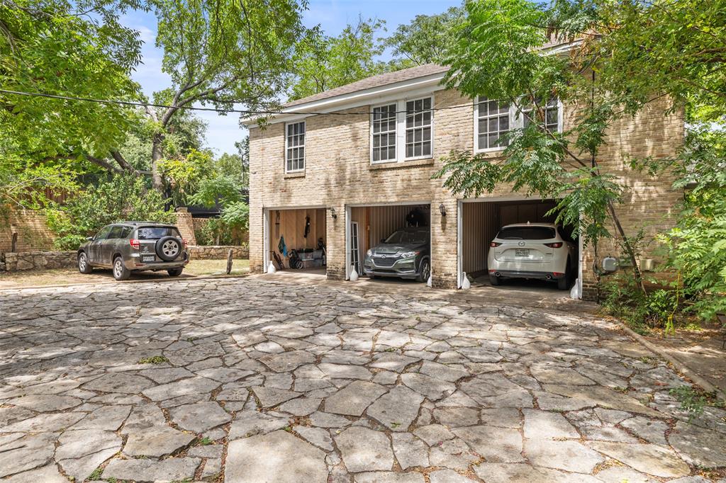 1806 Pearl Street Austin, TX 78701 - Photo 18 of 19 Stone-clad exterior featuring a three-car garage with individual bays, framed by mature trees