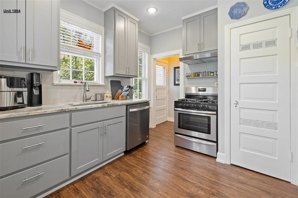 1806 Pearl Street Austin, TX 78701 - Photo 2 of 19 Kitchen featuring gray shaker-style cabinetry with chrome hardware, wood-finish flooring, stainless steel appliances, a tile backsplash, and light-toned countertops