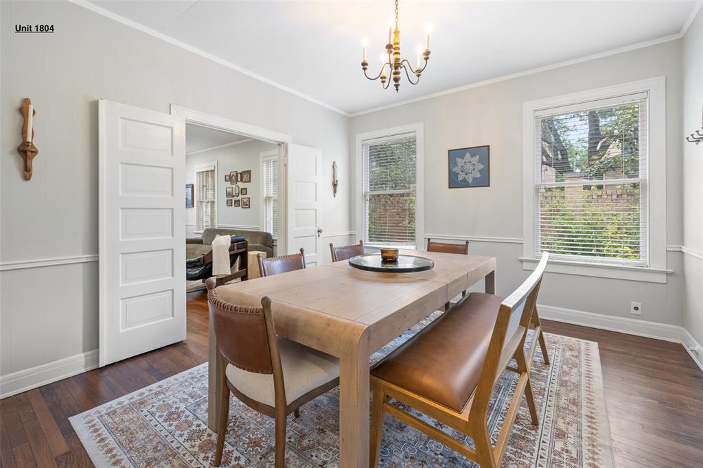 1806 Pearl Street Austin, TX 78701 - Photo 9 of 19 Dining area featuring wood-finish flooring, a brass chandelier, two large windows, white panel doors, and chair rail molding