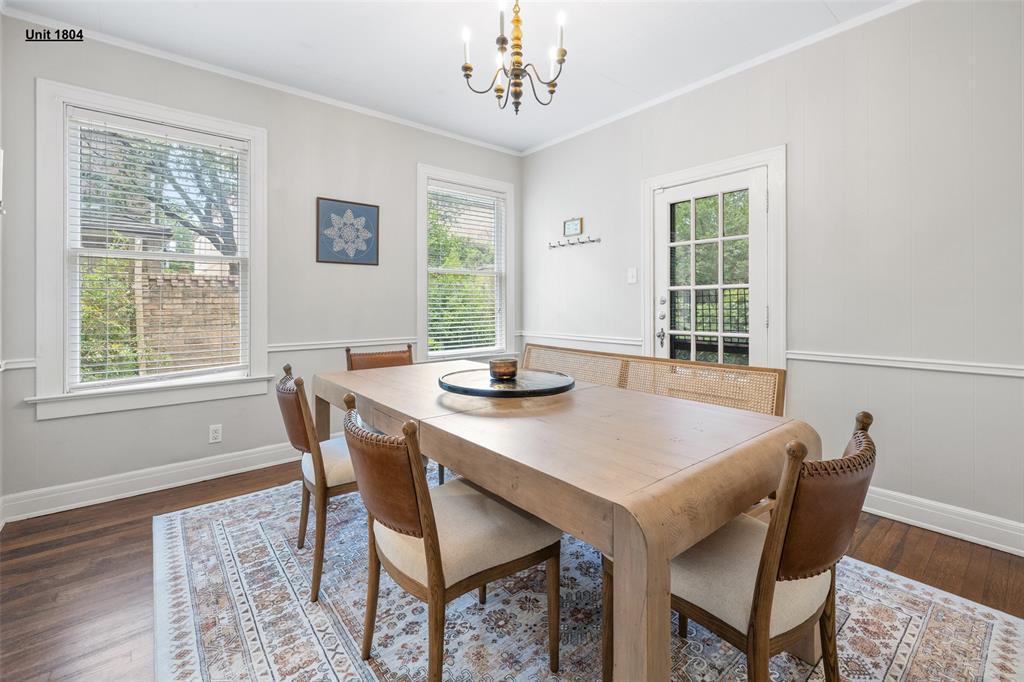 1806 Pearl Street Austin, TX 78701 - Photo 10 of 19 Dining space featuring wood-finish flooring, two large windows, a glass-paneled exterior door, a brass chandelier, and white wall trim
