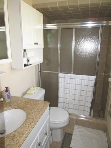 a bathroom with a granite countertop sink a toilet and shower