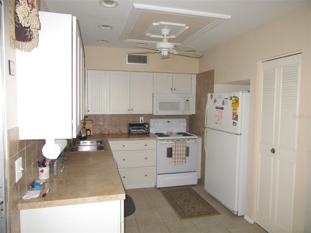 8158 Fay Avenue North Port, FL 34287 - Photo 6 of 23 a kitchen with a refrigerator and white cabinets