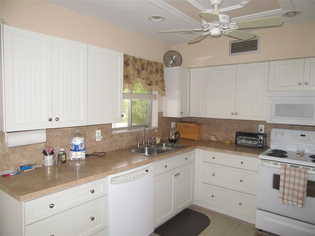8158 Fay Avenue North Port, FL 34287 - Photo 7 of 23 a kitchen with granite countertop white cabinets white appliances with a sink and dishwasher