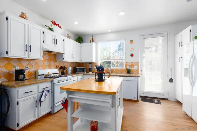 a kitchen with white cabinets and refrigerator