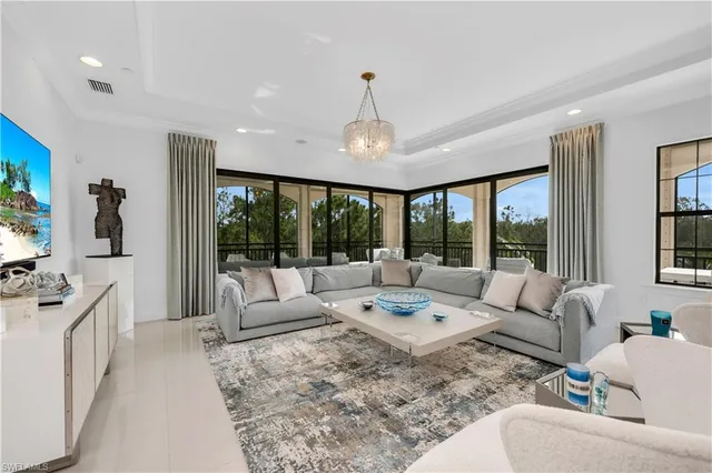 a living room with furniture large window and chandelier
