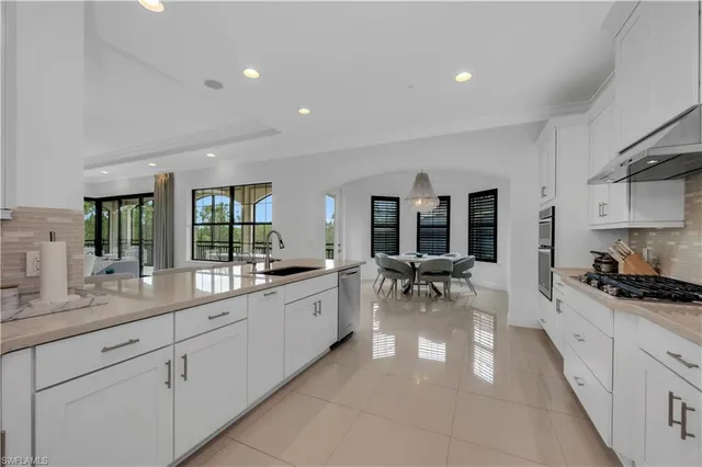 a large white kitchen with stainless steel appliances granite countertop a lot of white cabinets a stove and a sink