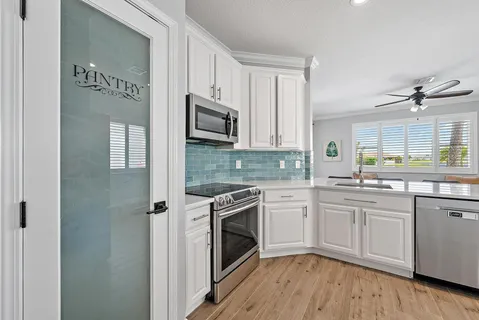 a kitchen with cabinets stainless steel appliances a sink and wooden floor