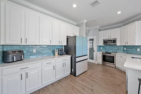 a kitchen with white cabinets white stainless steel appliances and wooden floors