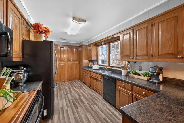 a kitchen with stainless steel appliances granite countertop wooden cabinets a stove top oven a sink and dishwasher with wooden floor