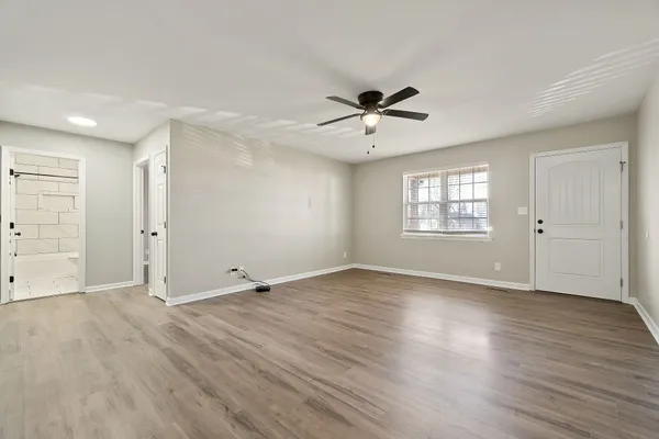 an empty room with wooden floor and windows