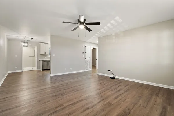 an empty room with wooden floor ceiling fan and windows