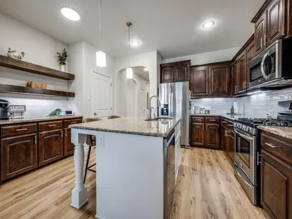 a kitchen with stainless steel appliances kitchen island granite countertop a stove a sink and a refrigerator
