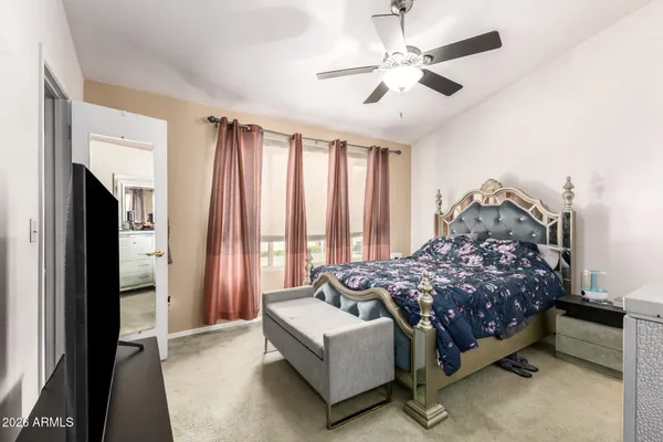 a bedroom with a bed couches and a flat tv screen