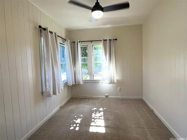 an empty room with windows and ceiling fan