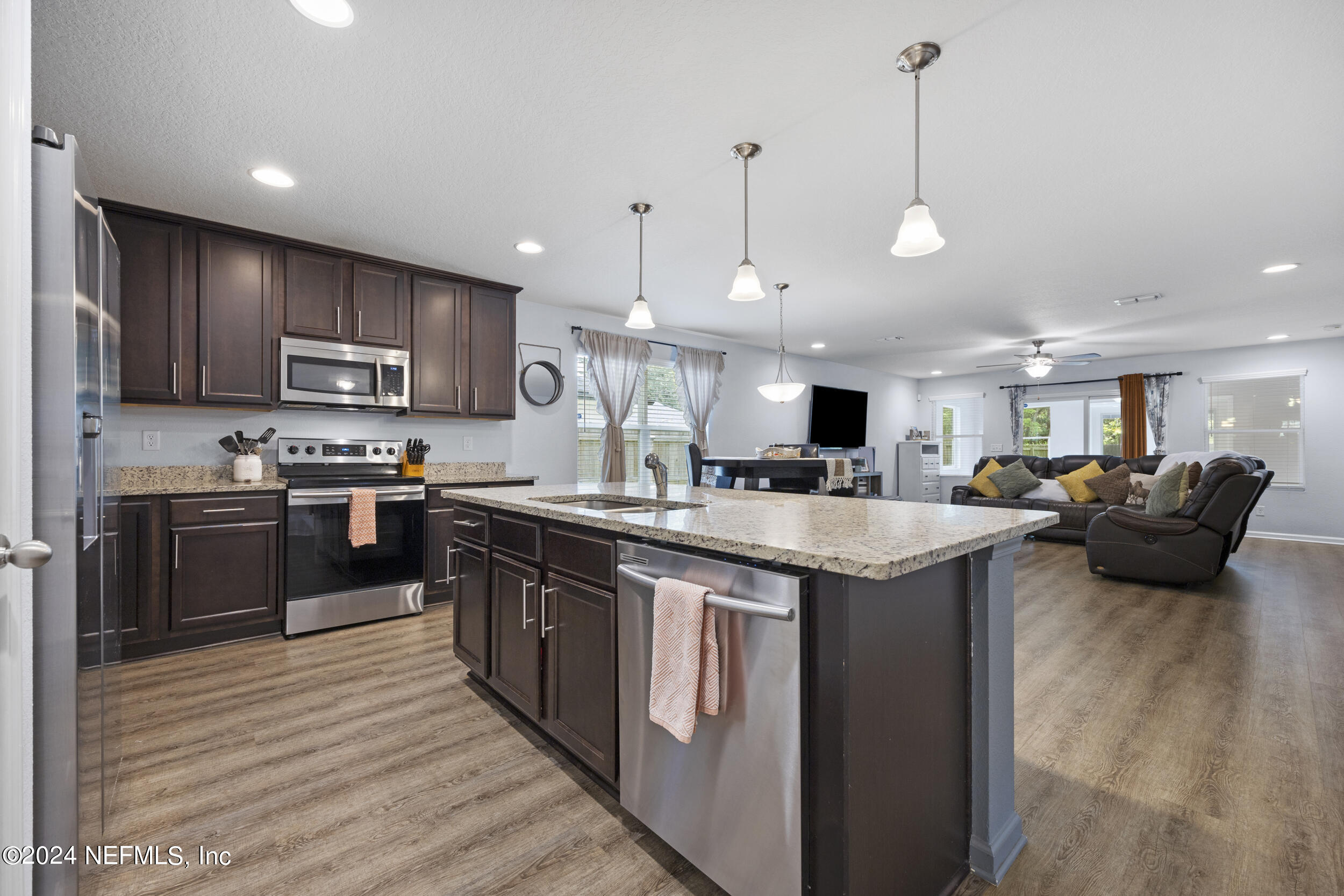 4021 Spring Glen Road Jacksonville, FL 32207 - Photo 5 of 39 a kitchen with stainless steel appliances kitchen island granite countertop a stove top oven a sink dishwasher a refrigerator and a dining table with wooden floor