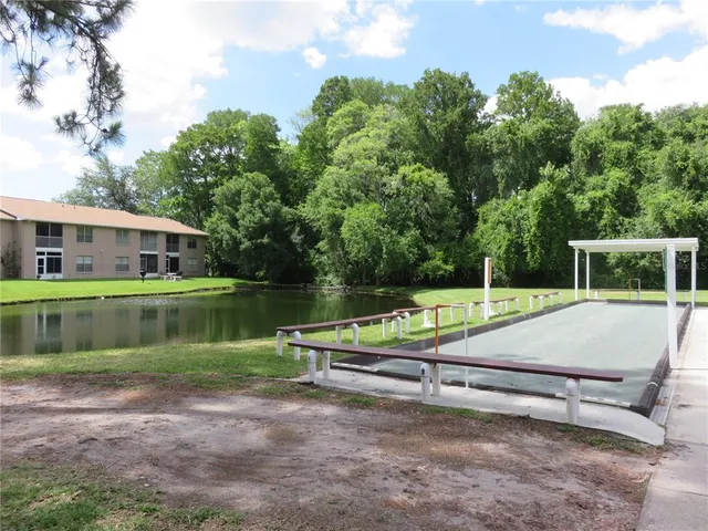 a view of swimming pool with outdoor seating and trees in the background