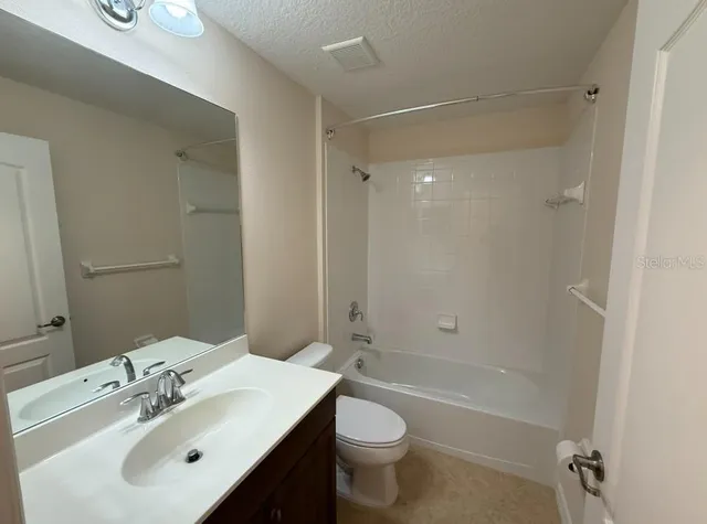 a bathroom with a bathtub shower sink vanity mirror and toilet
