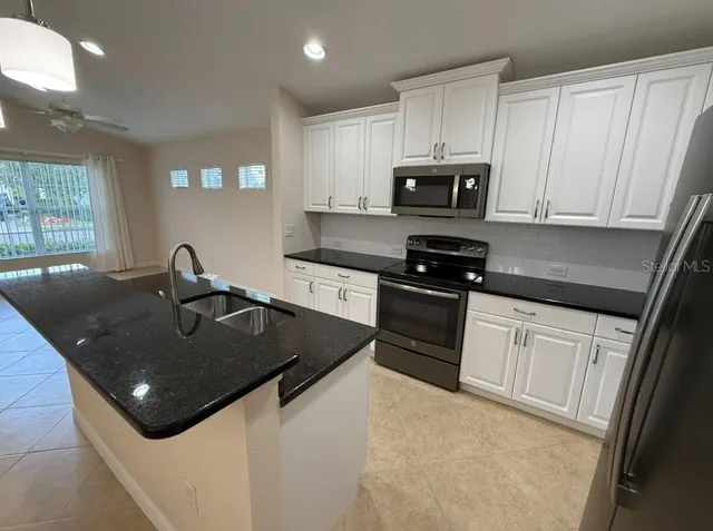 a kitchen with stainless steel appliances granite countertop a sink a stove and microwave