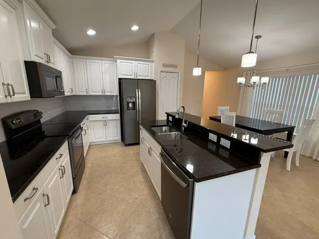 a kitchen with stainless steel appliances granite countertop a sink a stove and a refrigerator
