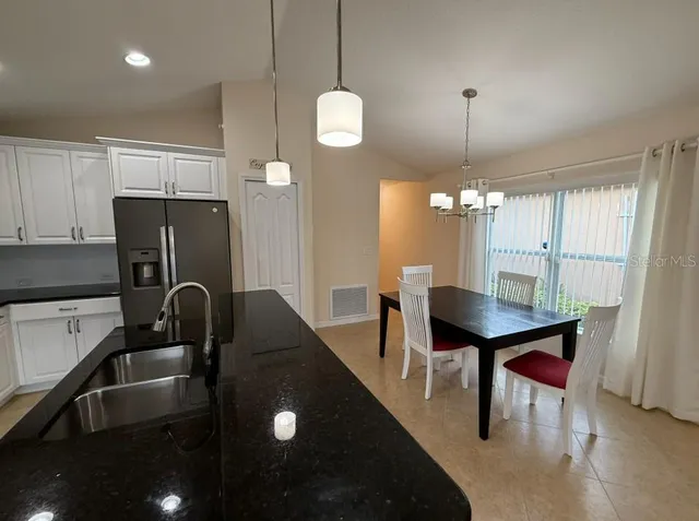 a kitchen with a refrigerator a sink dishwasher a stove and a dining table with wooden floor