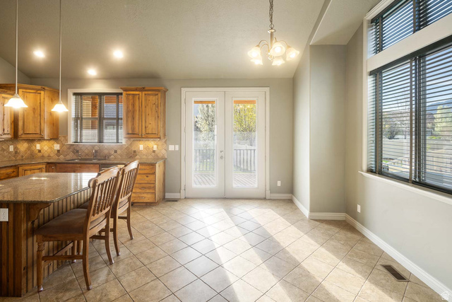 1997 West Cres Drive Mapleton, UT 84664 - Photo 10 of 35 Kitchen featuring french doors, dark stone countertops, wood finish cabinets, hanging lights, and vaulted ceiling